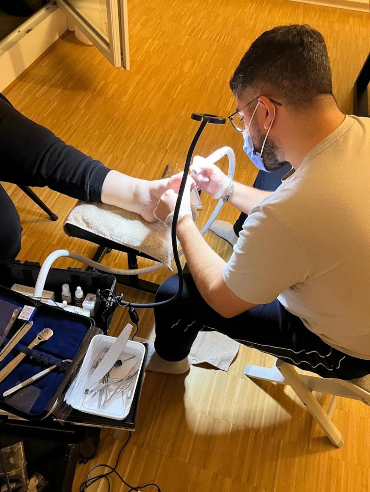 Sevket Öven behandelt einen Kunden zu Hause, mit Mundschutz, Handschuhen und mobilem Instrumentenkoffer